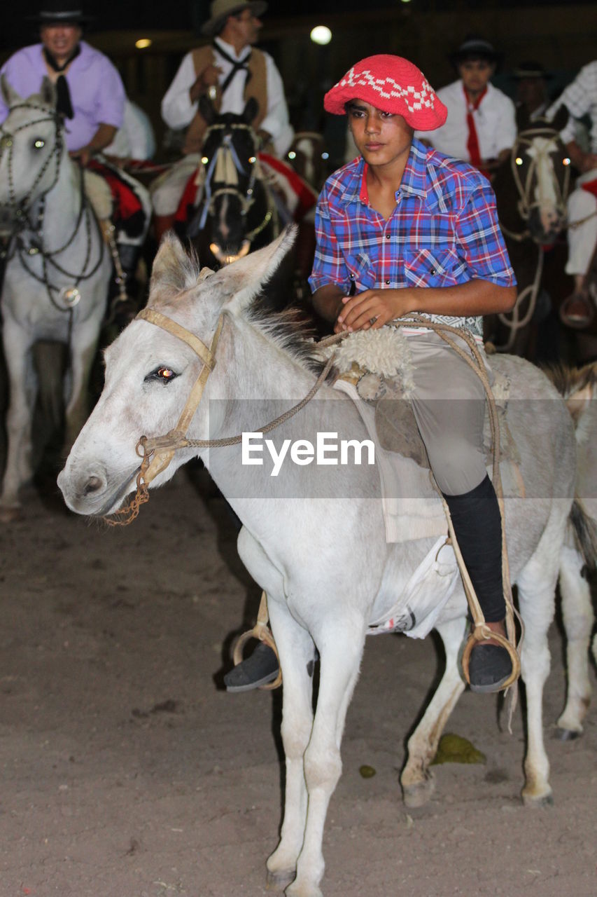 YOUNG MAN RIDING HORSE IN A FARM