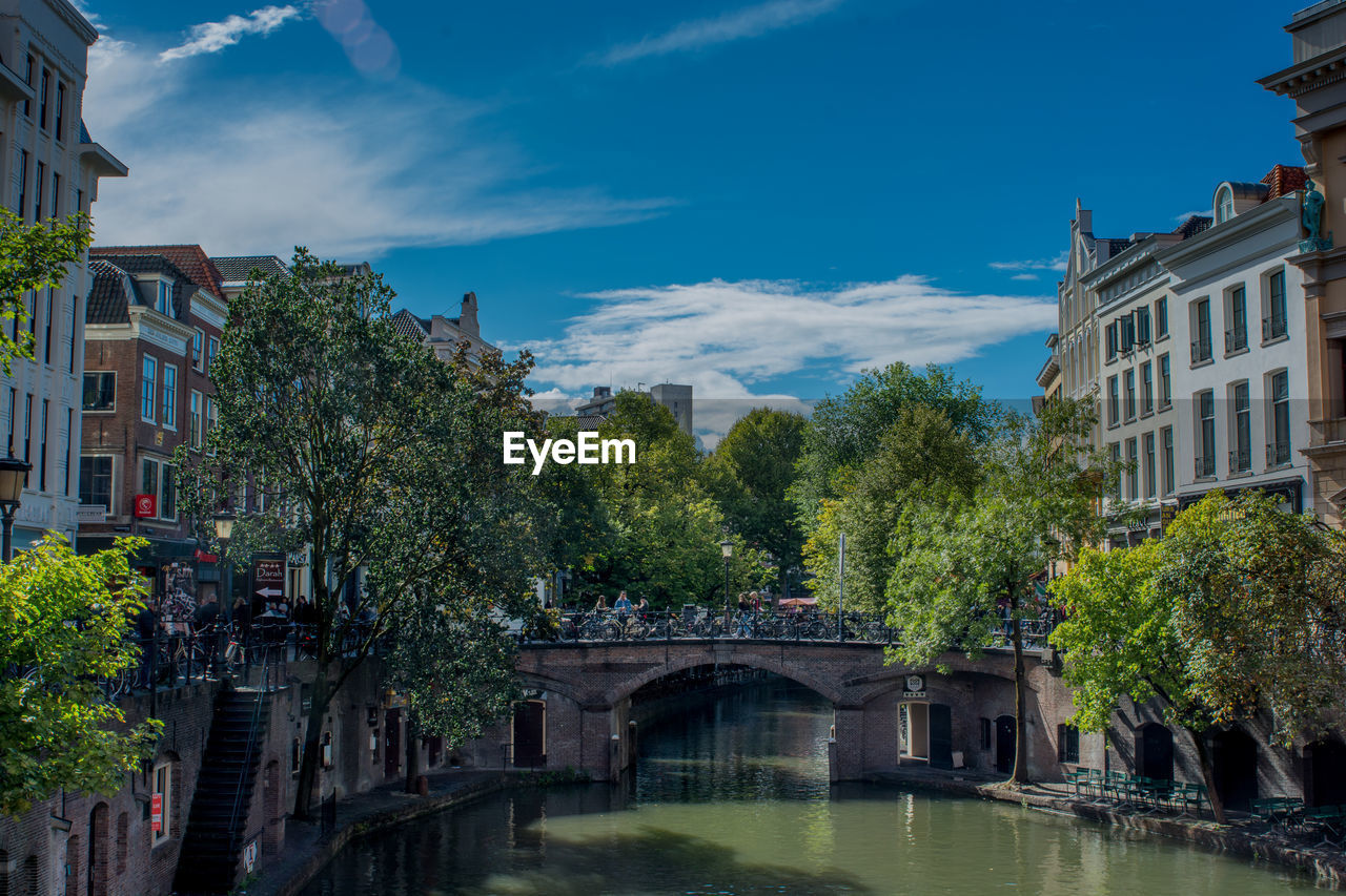 Arch bridge over river amidst buildings against sky