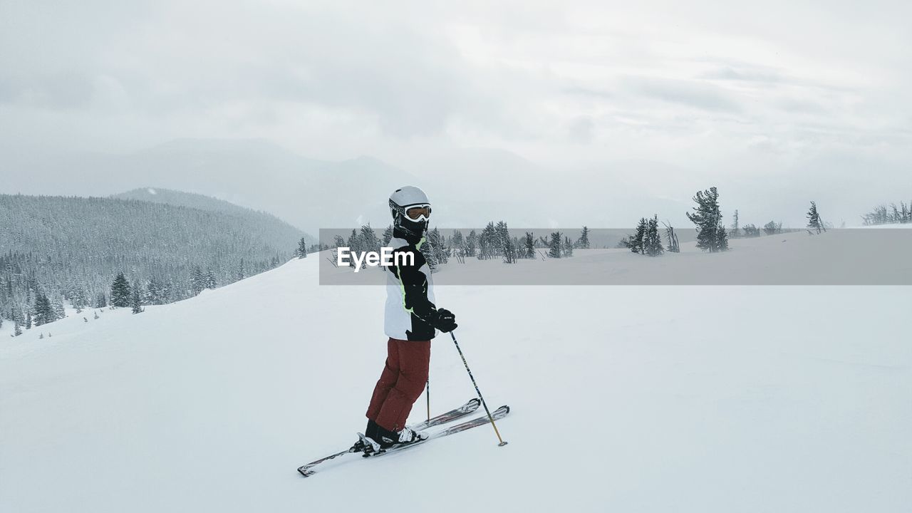 WOMAN SKIING ON MOUNTAIN AGAINST SKY