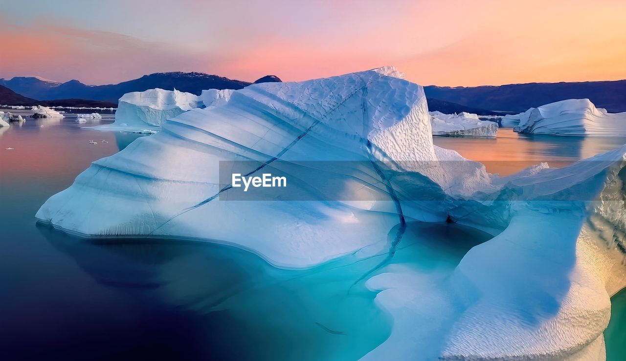 Iceberg floating in greenland fjord with sunset.