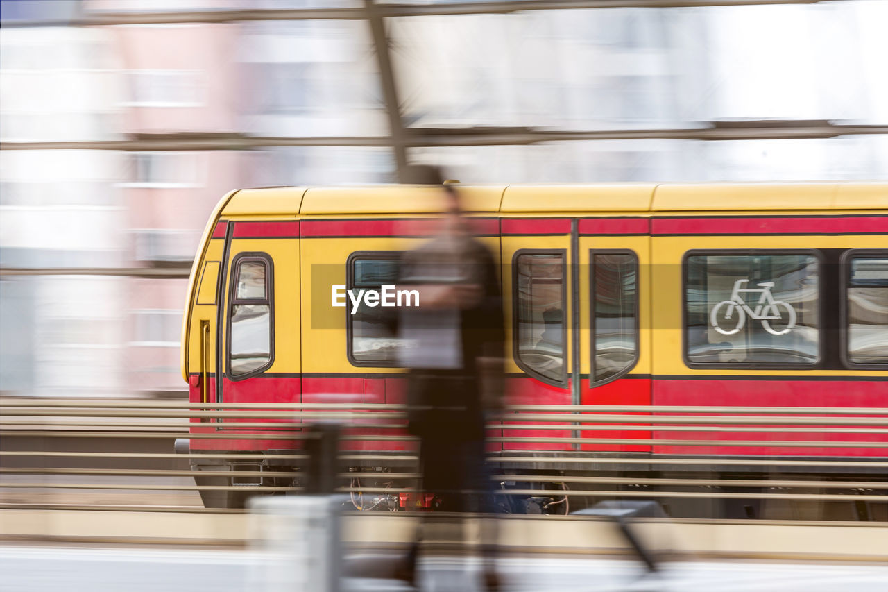 Blurred motion of person and train at railroad station platform