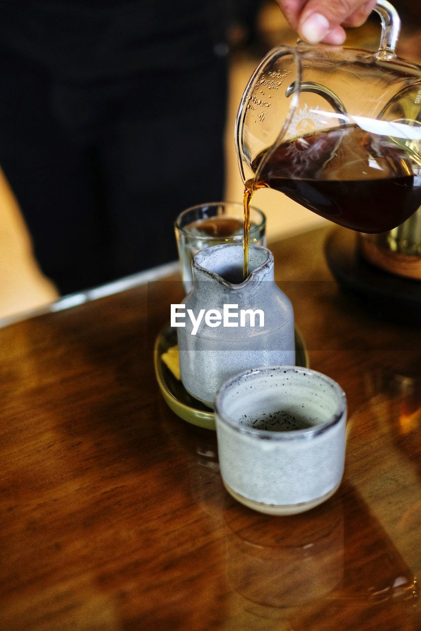 PERSON POURING COFFEE IN GLASS