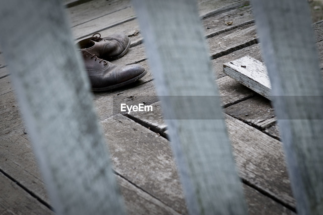 High angle view of shoes seen through wooden fence