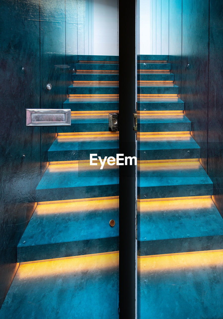 Empty staircase seen through glass door