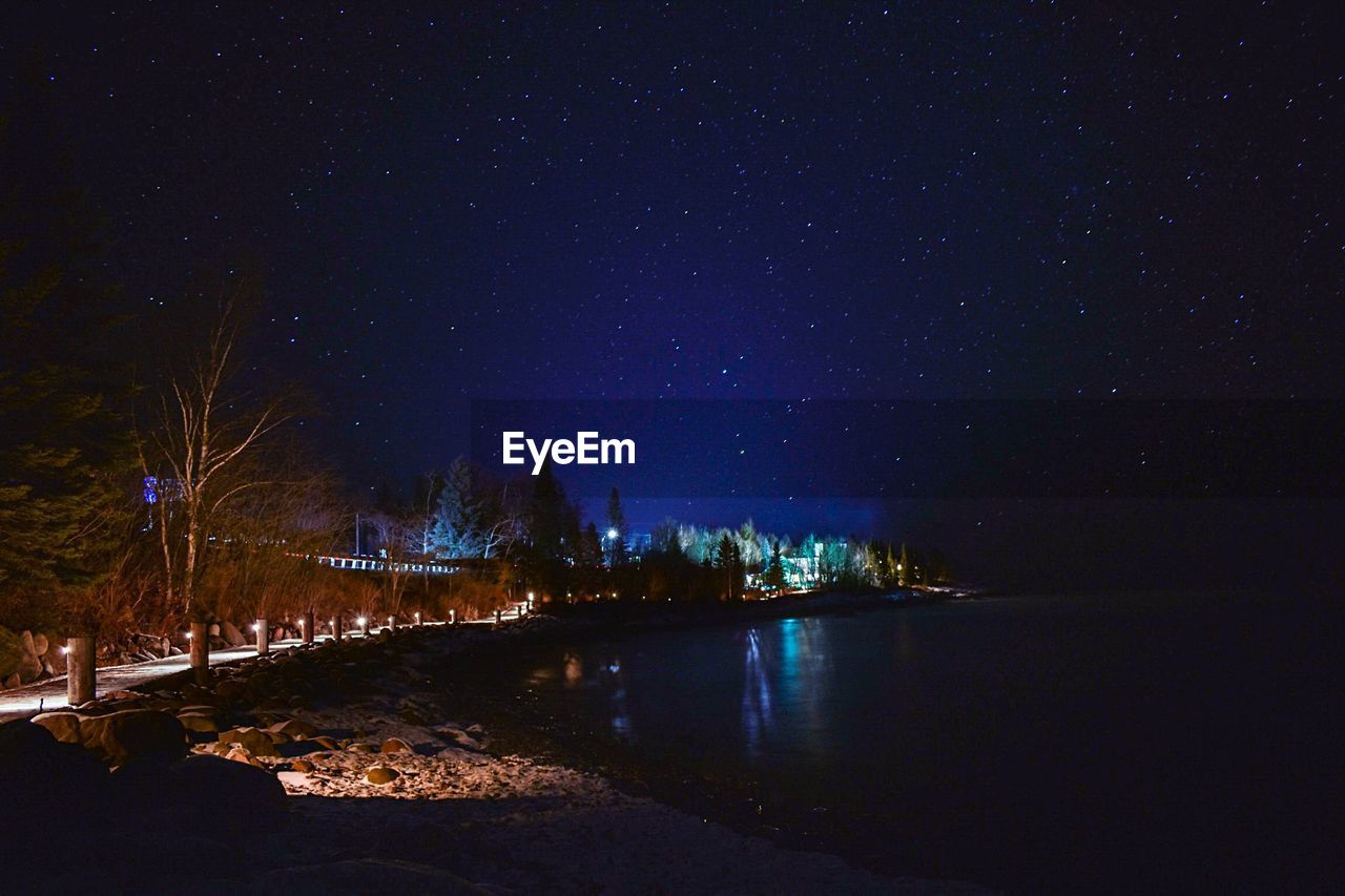 River amidst illuminated city against sky at night