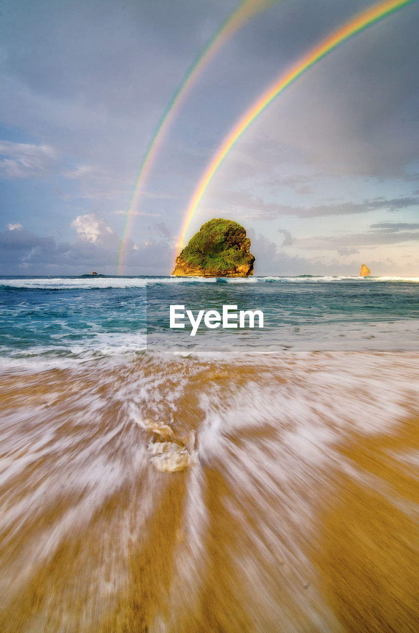 Scenic view of rainbow over sea against sky