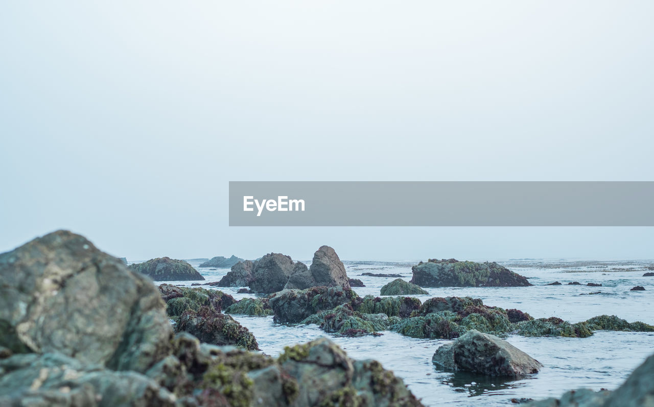 Rocks on beach against foggy sky