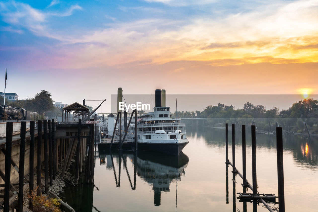 BOATS MOORED AT HARBOR DURING SUNSET