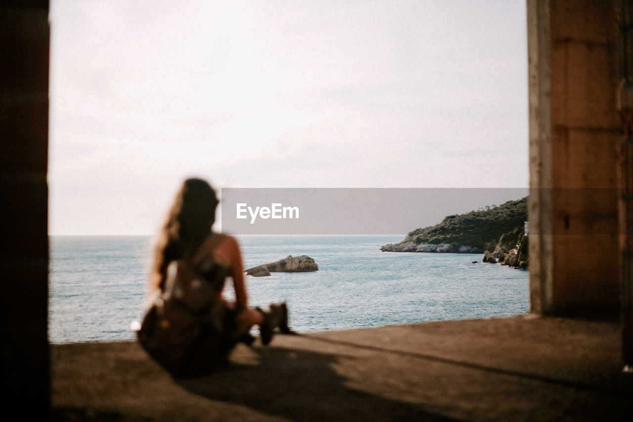 Woman looking at sea against sky