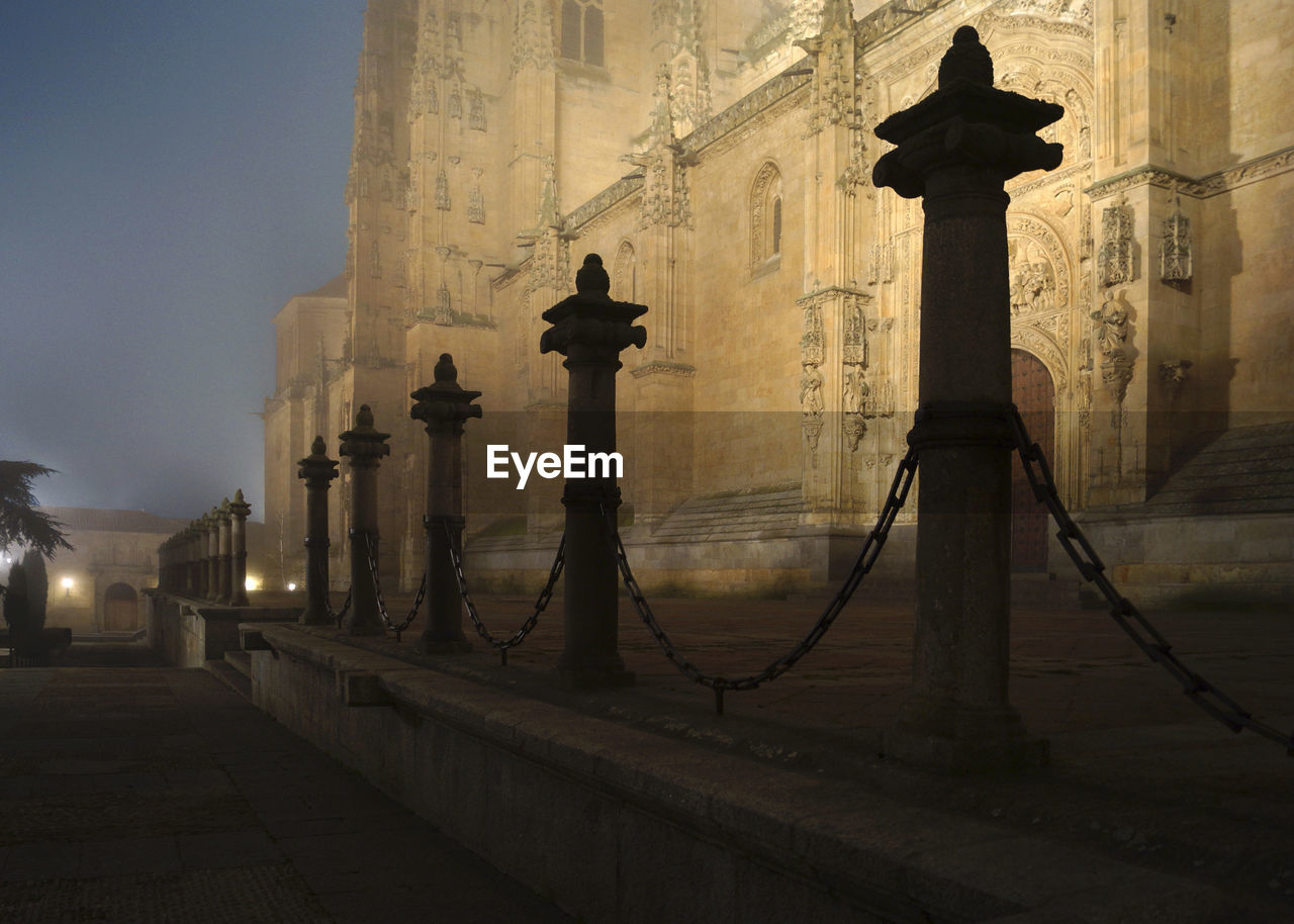 Bollards by illuminated historic cathedral at dusk