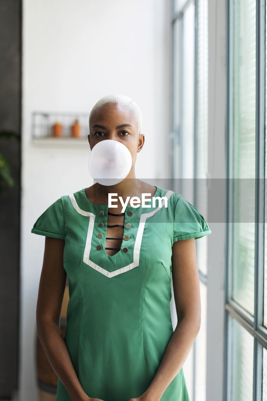 Woman wearing green dress making gum bubble