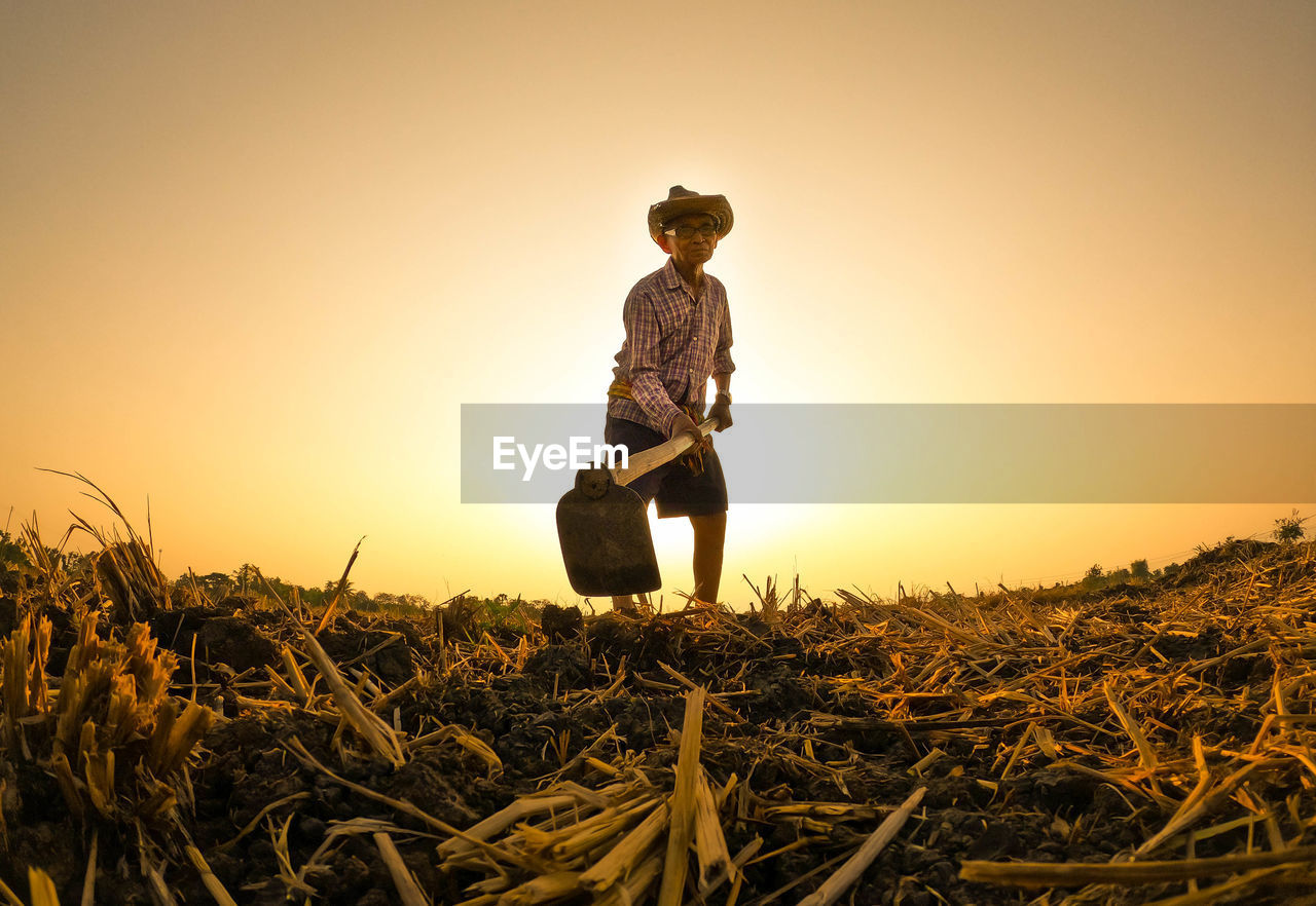 Man working on field against clear sky during sunset