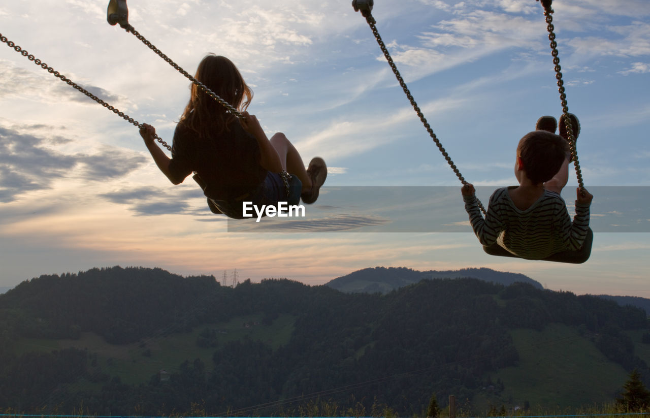 Low angle view of man swinging against mountain