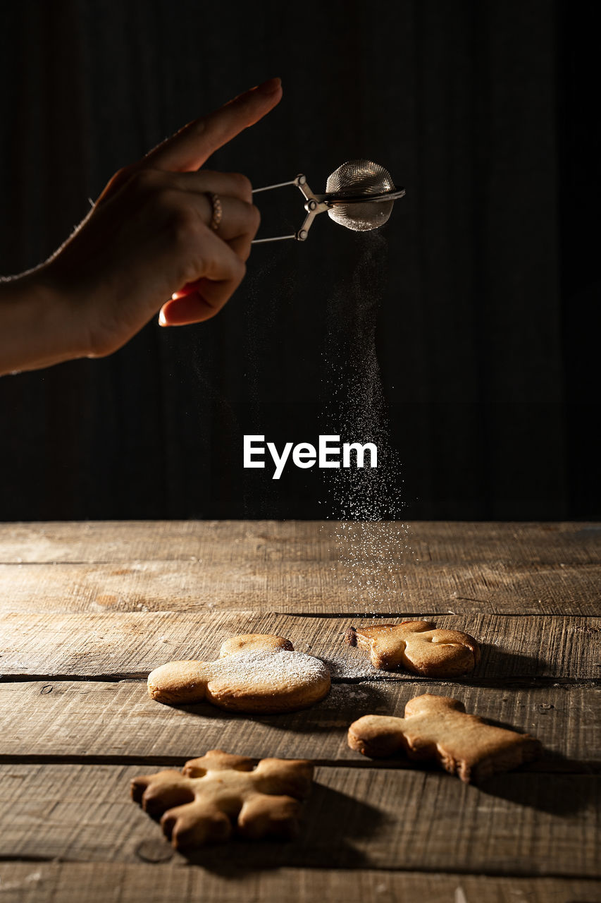 Close-up of hand dusting powder sugar on cookies