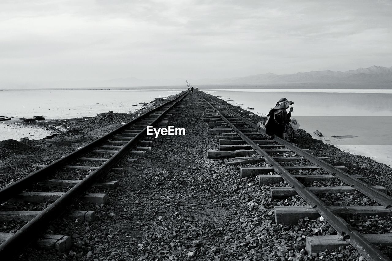 TRAIN ON RAILROAD TRACK BY SKY AGAINST CLOUDY DAY