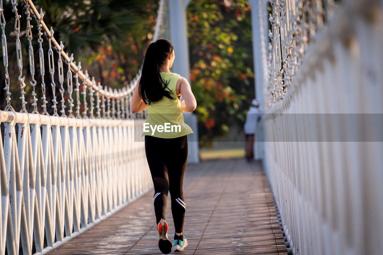 Rear view of woman running on footbridge
