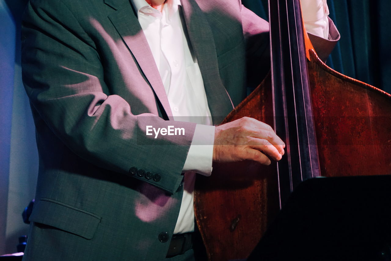 Midsection of musician playing double bass