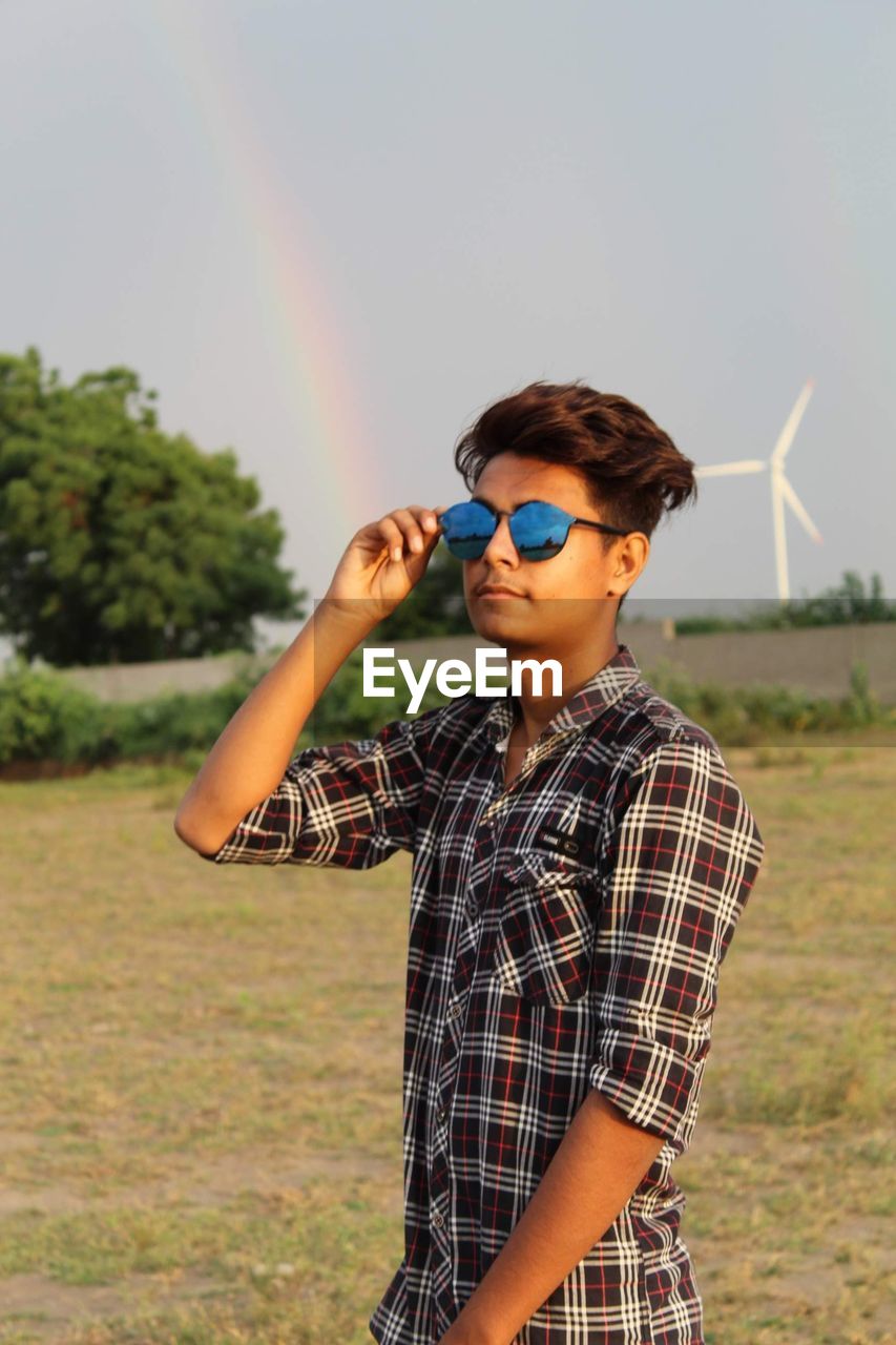 Boy wearing sunglasses standing on field