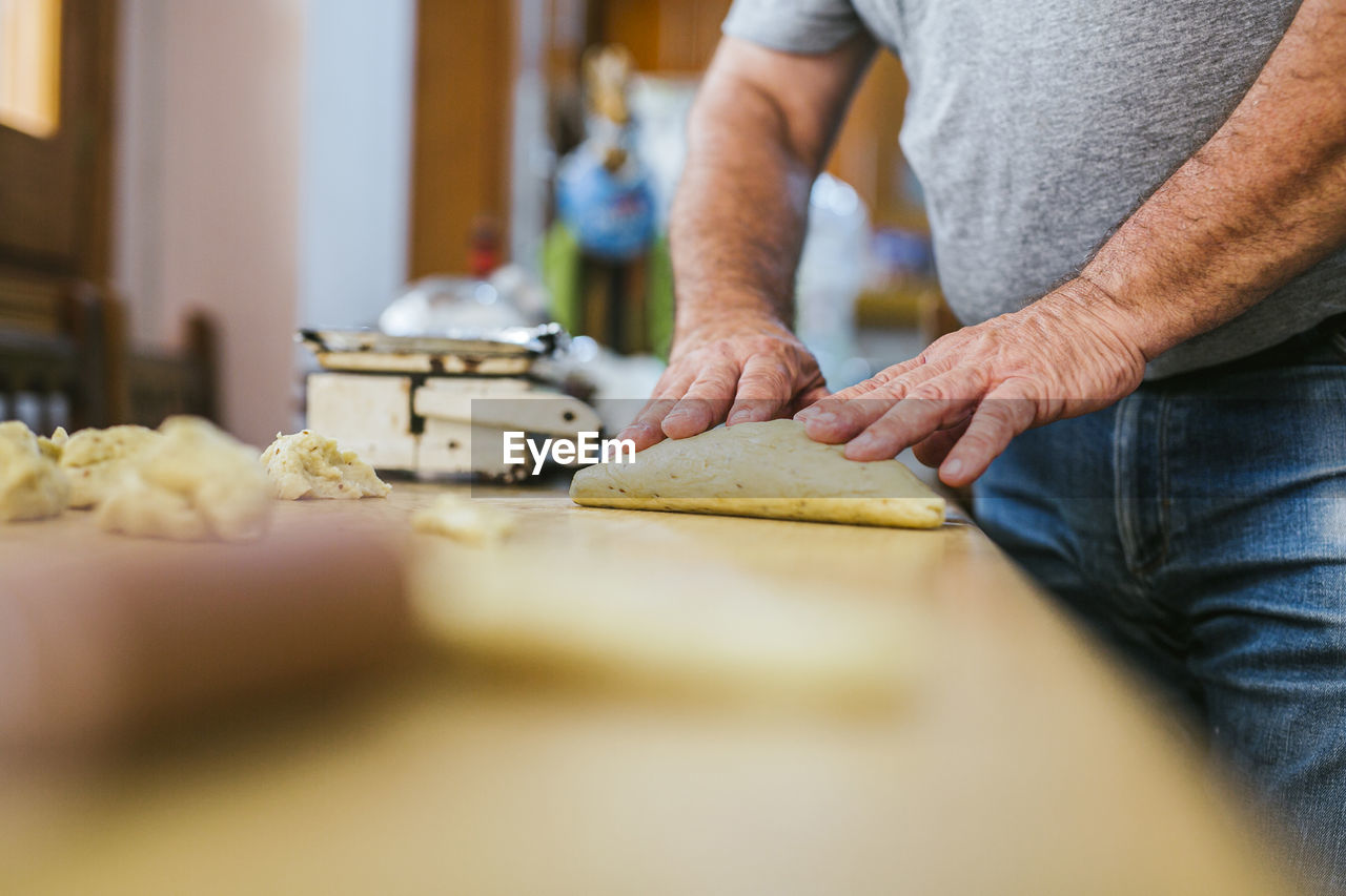 Midsection of chef preparing fresh mona de pascua on kitchen counter at restaurant