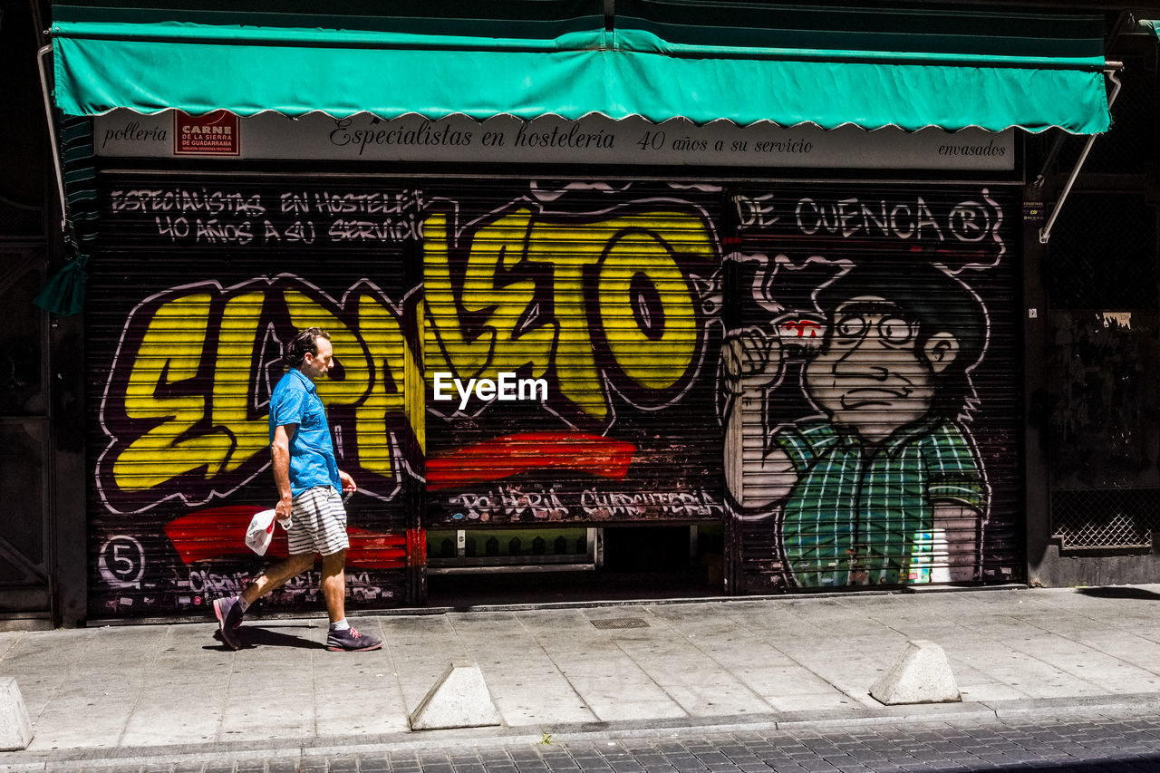 FULL LENGTH OF MAN STANDING IN GRAFFITI