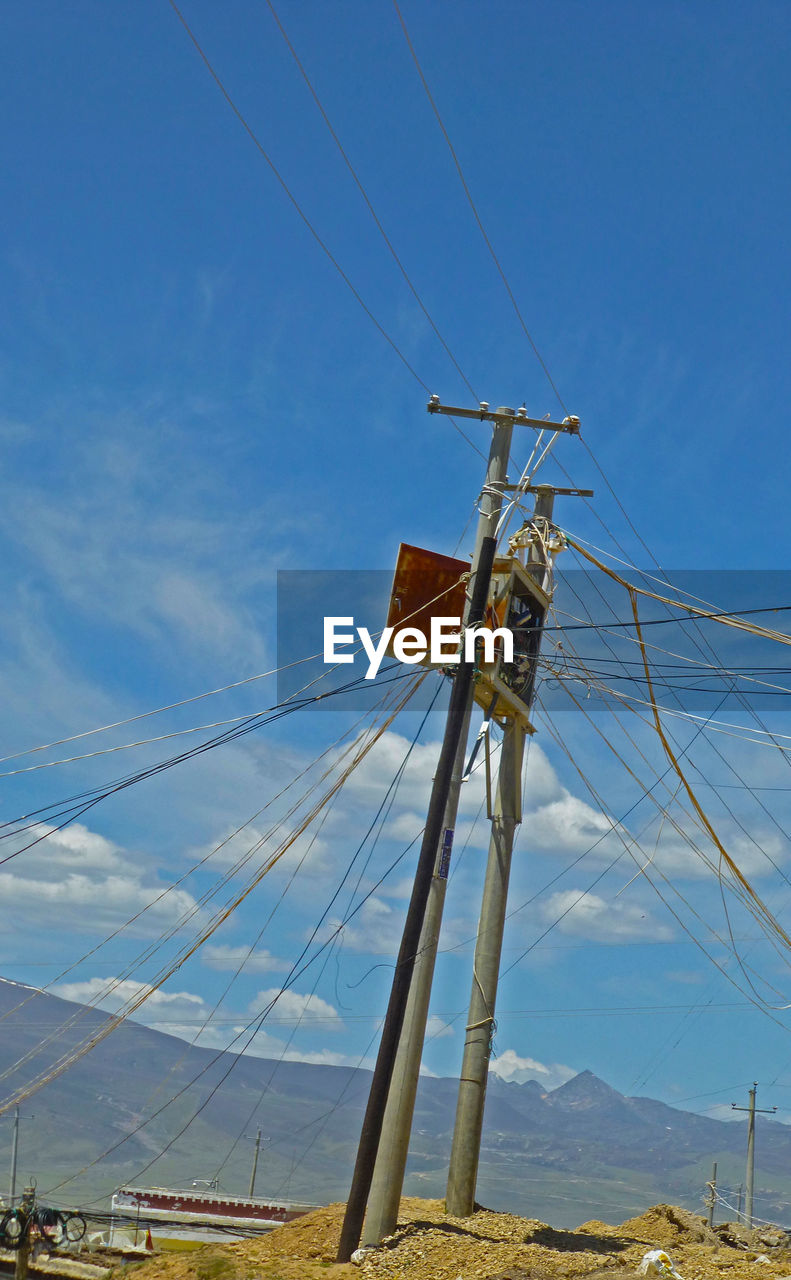 LOW ANGLE VIEW OF ELECTRICITY PYLONS ON FIELD AGAINST SKY