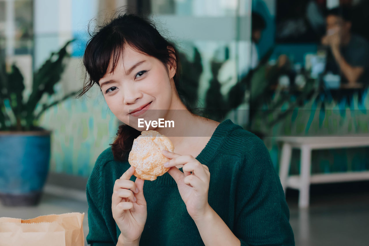 Portrait of woman holding food in restaurant