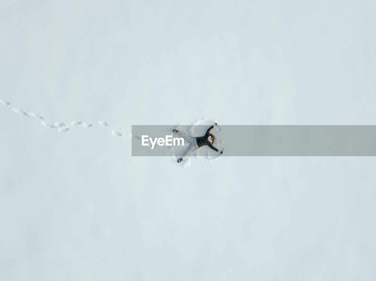 High angle view of young woman making snow angel