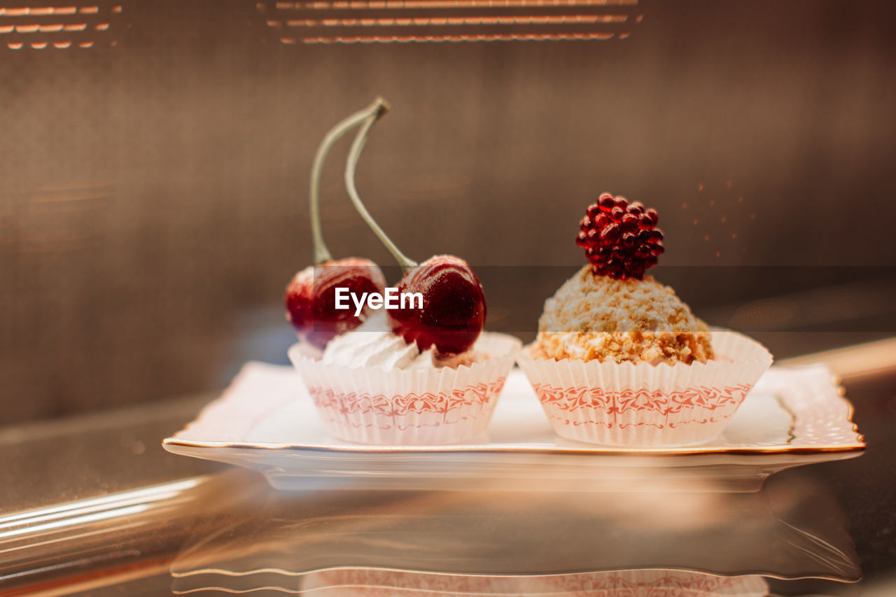 Sweet tiny cakes with fluffy cream and red cherries