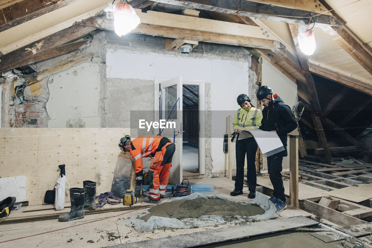 Full length of female building contractor discussing with male worker at site