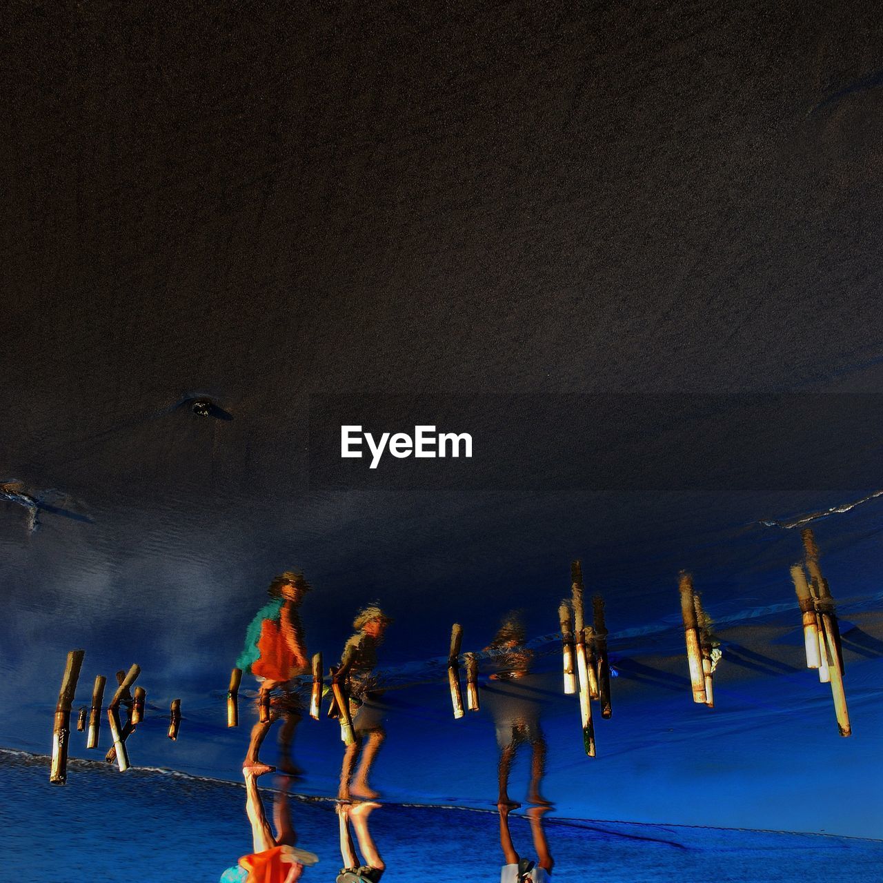 Upside down image of people reflecting on wet sand