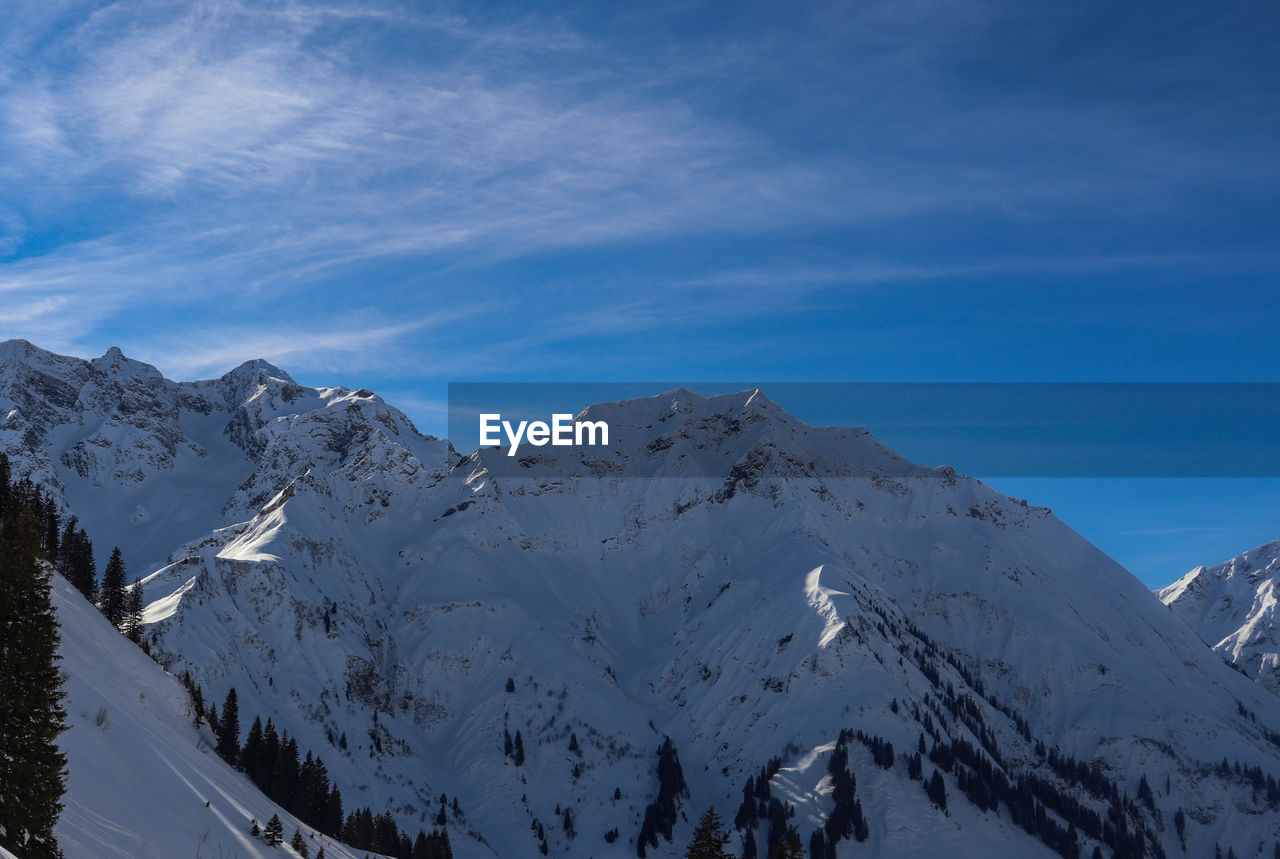 Scenic view of snowcapped mountains against blue sky