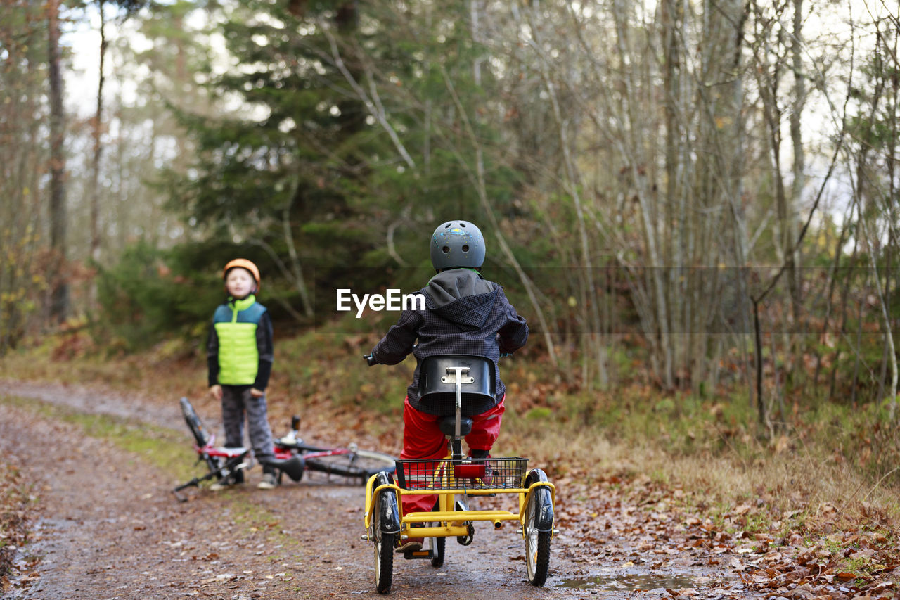 Boys cycling through forest