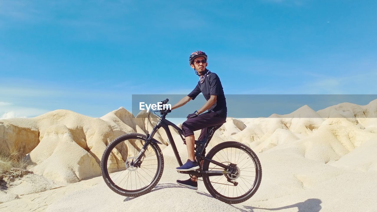 Man riding bicycle on mountain against sky