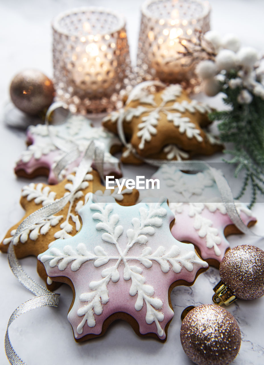 Christmas gingerbread cookies on marble table decorated with garland and candles.