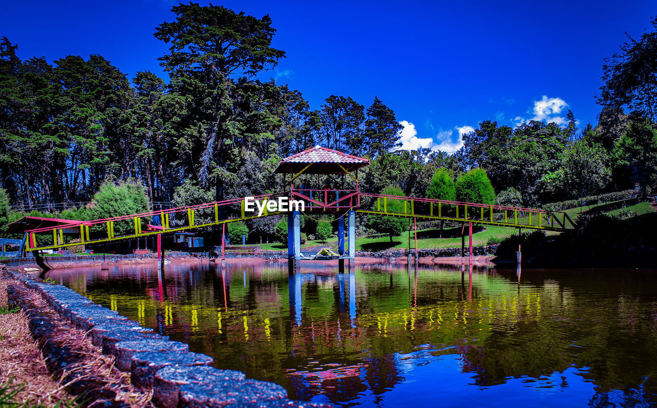 BRIDGE OVER LAKE AGAINST TREES