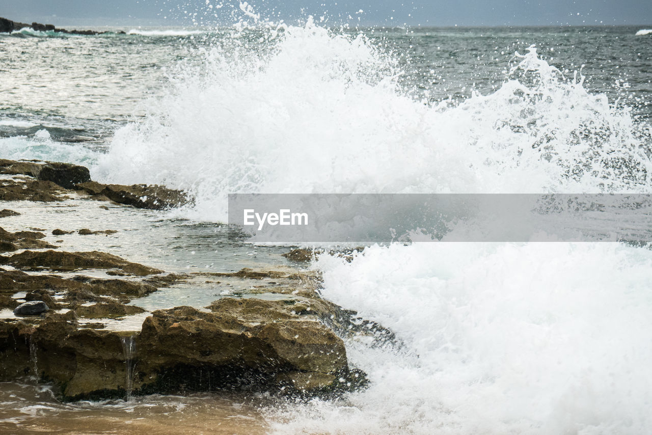 WAVES SPLASHING ON ROCKS AT BEACH