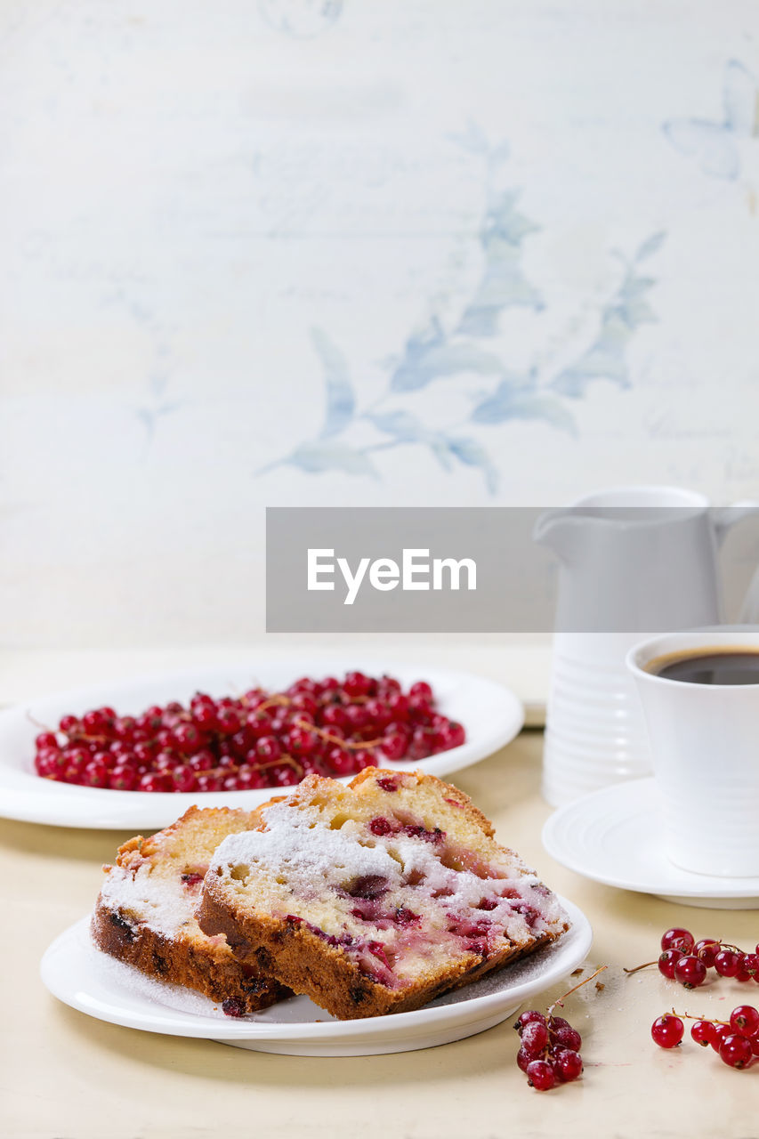 High angle view of red currants with cake slices on table