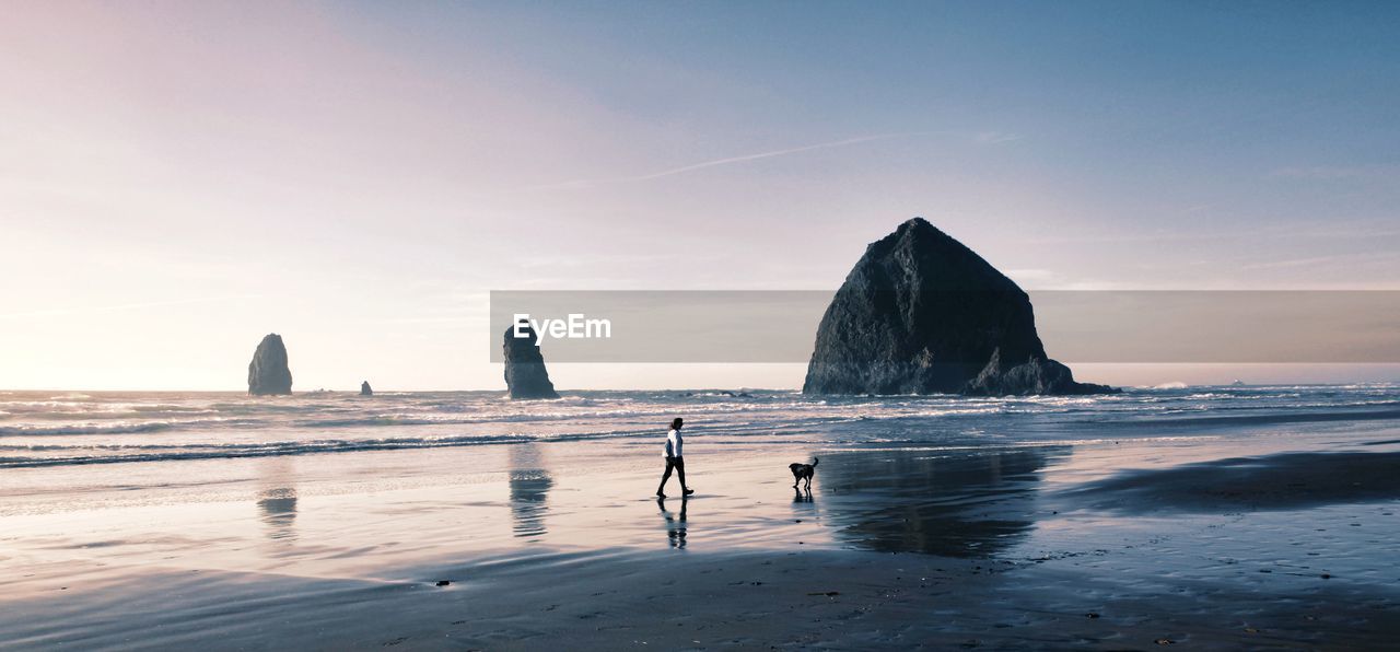 Rocks on beach against sky during sunset