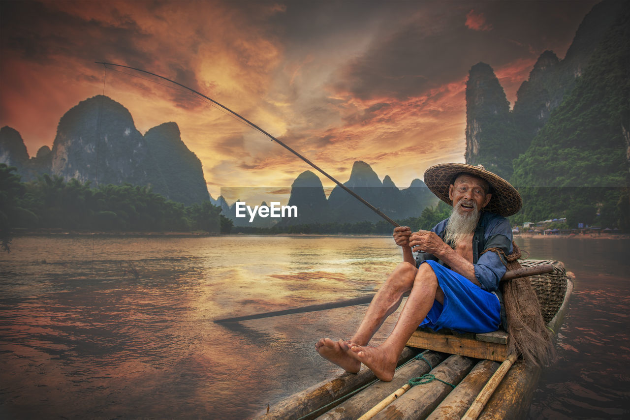 Portrait of man fishing in lake against sky during sunset