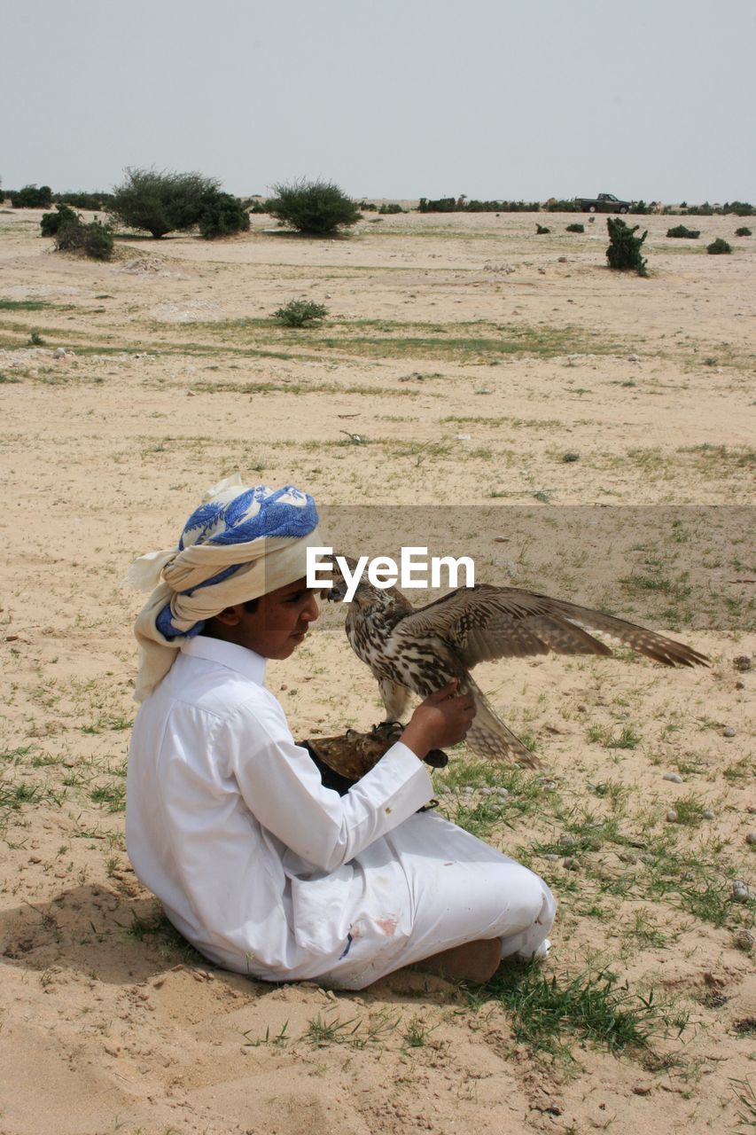 MAN SITTING ON FIELD