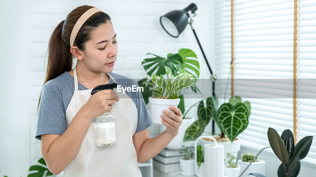 YOUNG WOMAN LOOKING AT POTTED PLANTS