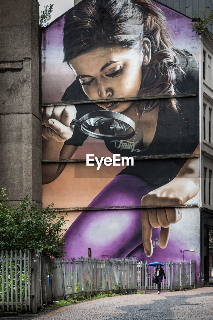 PORTRAIT OF YOUNG WOMAN AGAINST BUILDING WALL