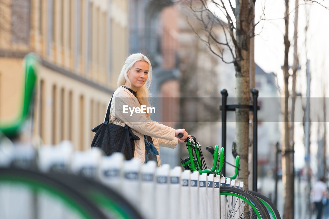 Portrait of woman with bicycle standing in city