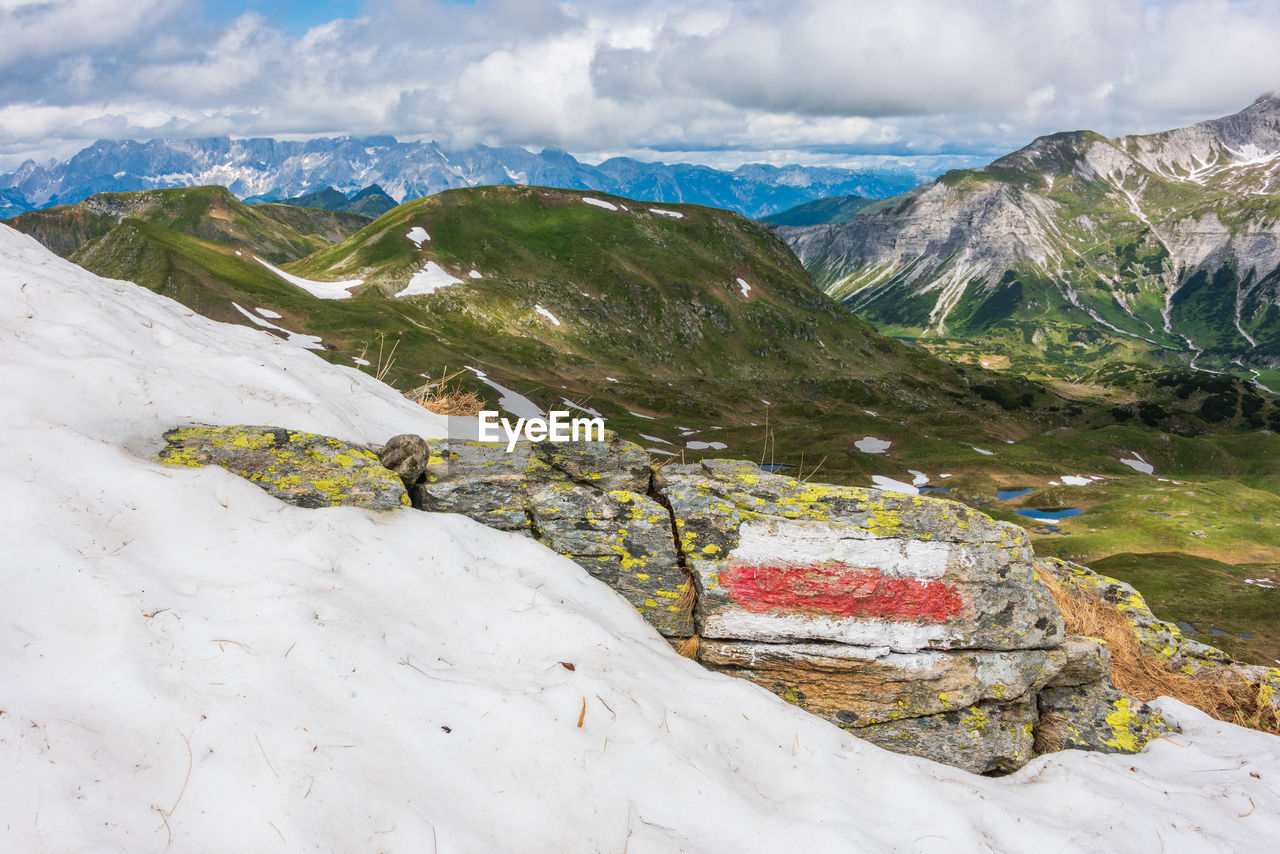 Red and white marking of the hiking trail in the austrian alps. sunny mountain panorama with snow