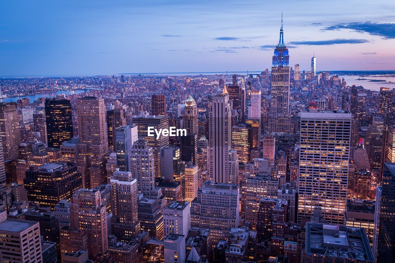 Aerial view of city lit up against sky