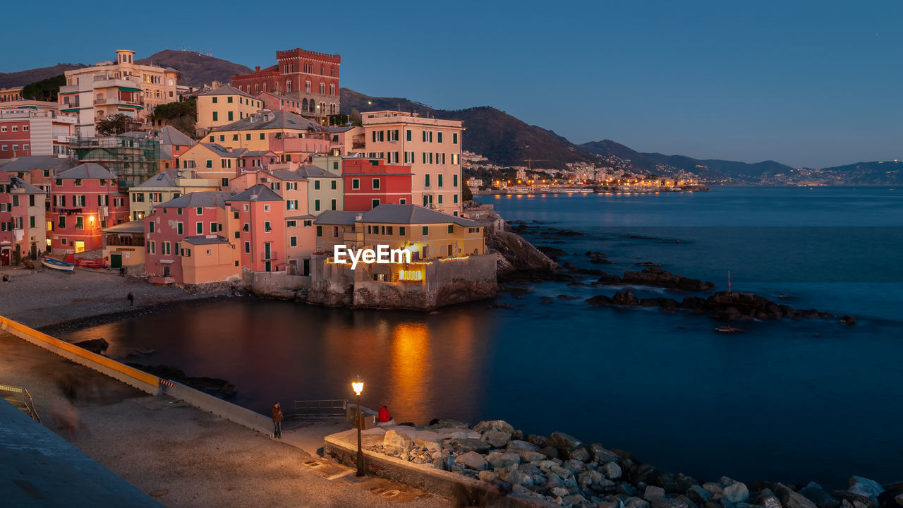 Buildings by sea against sky at dusk