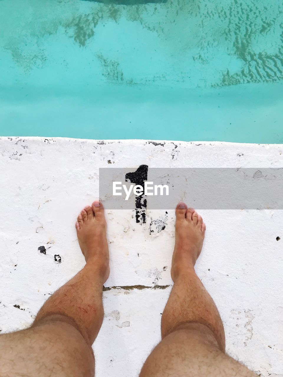 Low section of man standing at poolside