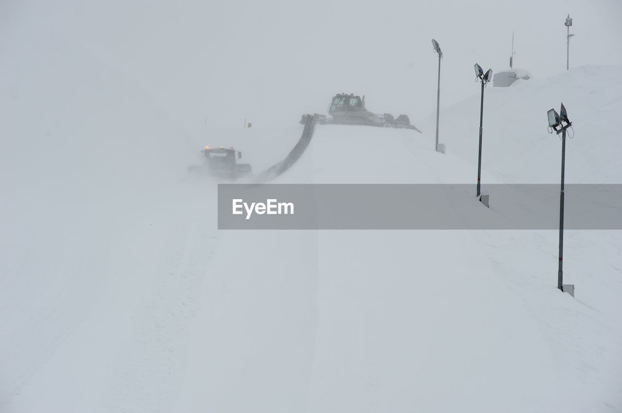 Snow groomer by street lights on field