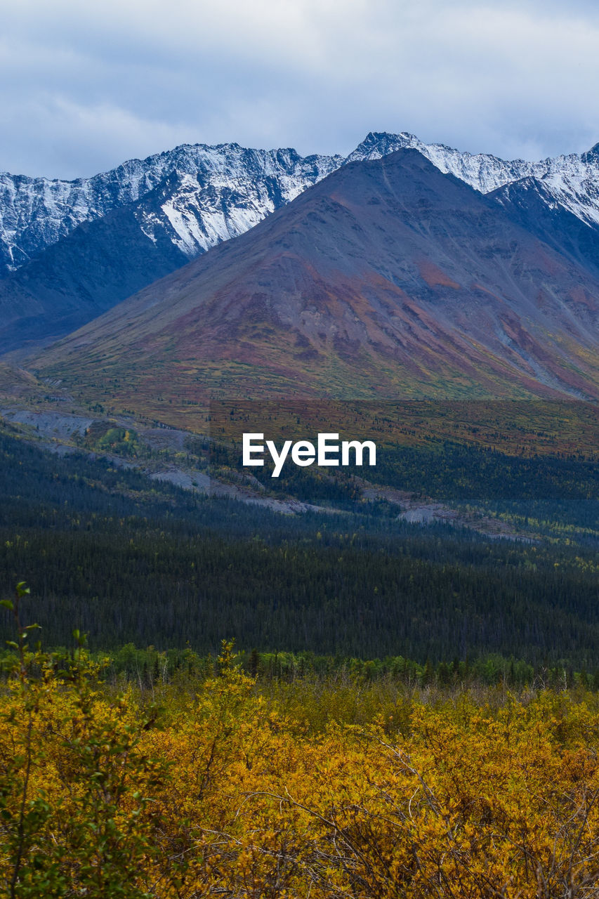 Scenic view of snowcapped mountains with autumn colours against sky