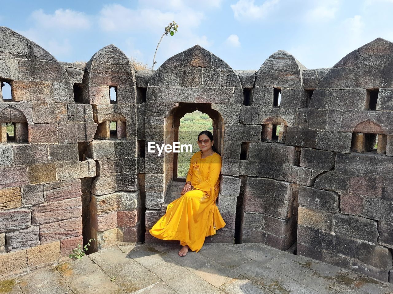 Full length of woman sitting by fort wall